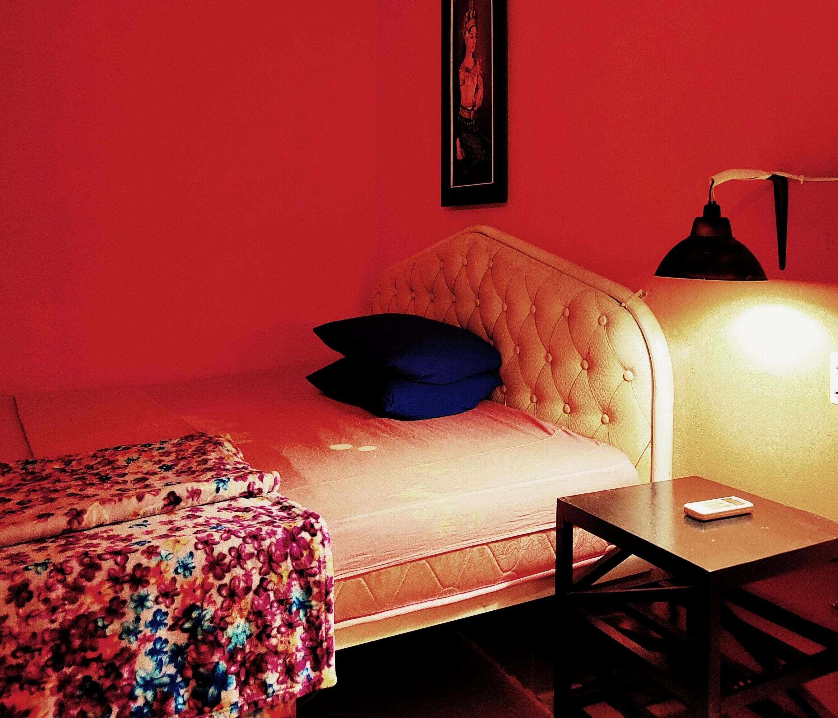 Une chambre avec un lit, une table de chevet, une lampe et une couverture à motifs floraux.