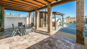 A covered patio area with a pool, outdoor seating, and a stone fireplace. - Nice home in Casariche (Casariche)