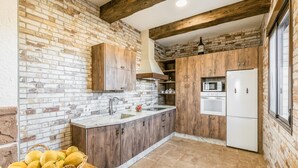 A kitchen with a brick wall, wooden cabinets, a white refrigerator, and a microwave. - Nice home in Casariche (Casariche)