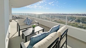 Un balcón con sofá, mesa y sillón, con vistas a la ciudad.