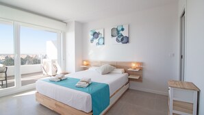 Un dormitorio moderno con una cama grande, un balcón con una silla y dos obras de arte abstracto en la pared.