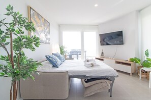 Une chambre d’hôtel moderne équipée d’un lit, d’une télévision, d’un bureau et d’une grande fenêtre.