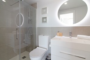 Une salle de bain moderne avec une douche à parois de verre, des toilettes et un meuble-lavabo avec un miroir.