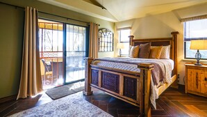 Un dormitorio con una cama grande, un ventilador de techo y vistas al exterior a través de un ventanal corredero.