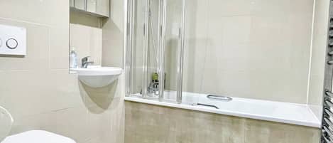 A bathroom with a toilet, sink, and shower area.