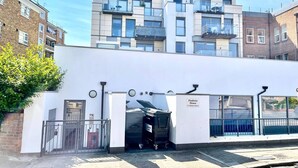 Un edificio moderno con fachada blanca, entrada protegida por una reja y un cartel que indica 'Pindoria House 52 Minster Street'.