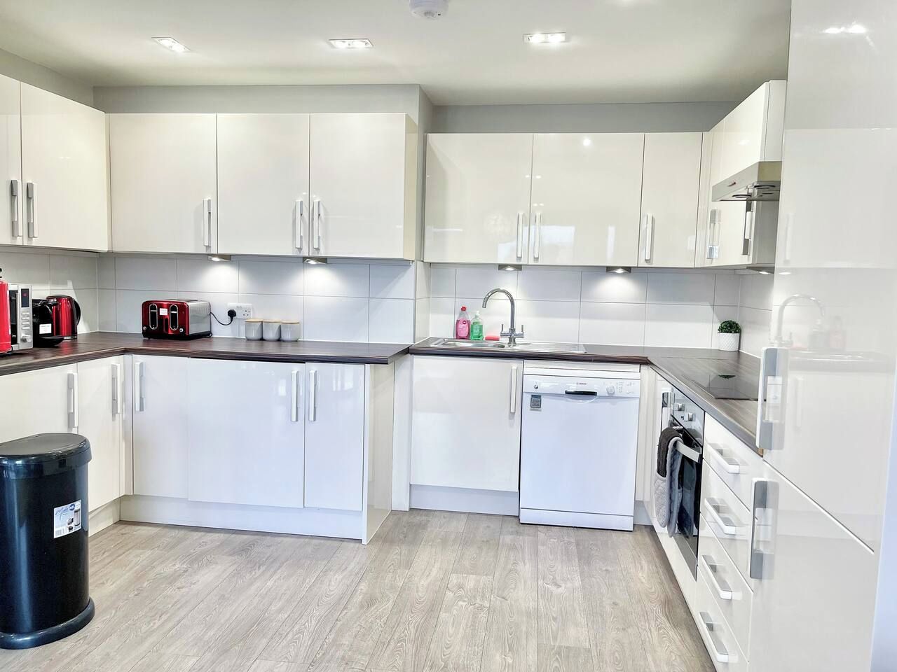 A modern kitchen with white cabinets, a dishwasher, and a coffee maker.