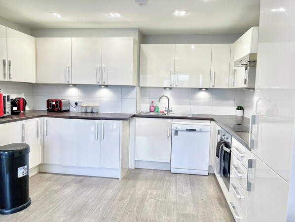 A modern kitchen with white cabinets, a dishwasher, and a coffee maker.