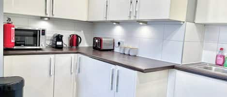 A modern kitchen with white cabinets, a microwave, a coffee maker, and a toaster.
