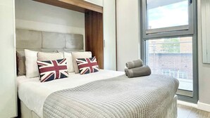 Un dormitorio con cama, almohadas, una ventana y vistas al exterior.