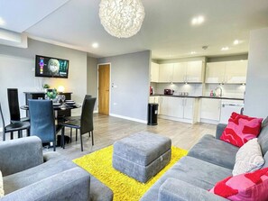 Una sala de estar moderna con un sofá gris, un tapete amarillo y un comedor con una mesa y sillas.