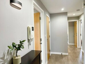 Un pasillo con un teléfono, una planta en maceta y puertas de madera.