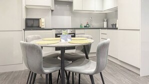 Una cocina moderna con armarios blancos, una mesa redonda con sillas y un microondas.