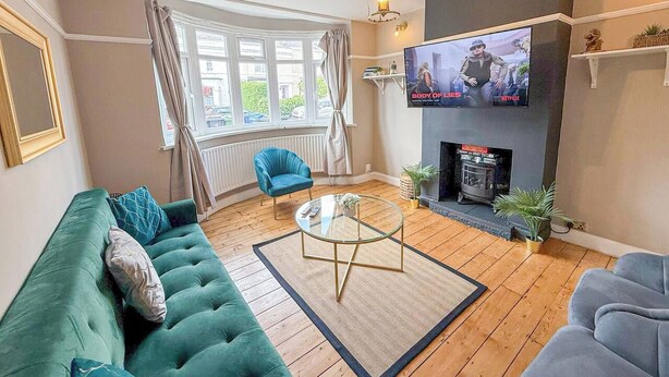 Una sala de estar con sofá, sillón, mesa de centro, chimenea, televisor y ventanas.