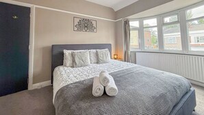 Una habitación de hotel con una cama, un ventanal y una puerta.