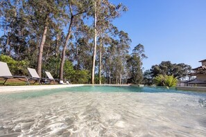 A clear swimming pool surrounded by lounge chairs and tall trees. - Villa da Floresta (Vila do Conde)