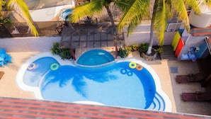 A swimming pool with a unique design, surrounded by palm trees and a covered seating area. - Hotel Marlin Mi Paraiso (Taxisco)