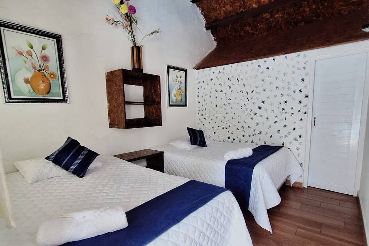 Ein Zimmer mit zwei Betten, Holzboden und einem Wandmuster.