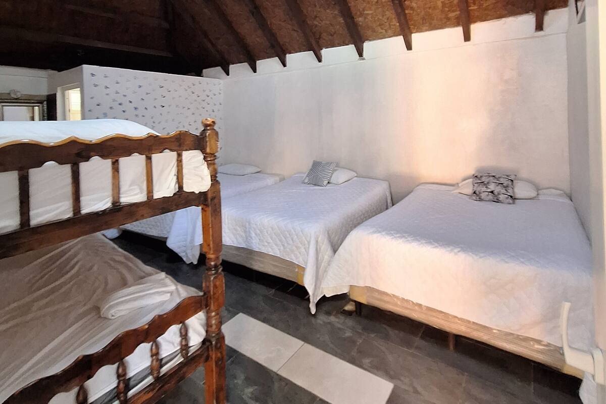 Ein Zimmer mit zwei Einzelbetten, einer hölzernen Bank und einem gefliesten Boden.