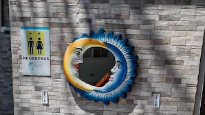 A public restroom with two sinks, a mirror with a blue and orange design, and a sign indicating gender-specific facilities. - Hotel Marlin Mi Paraiso (Taxisco)