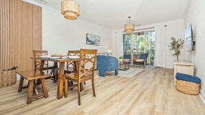 Een eethoek met houten meubels, een groot raam met gordijnen en uitzicht op de omgeving.