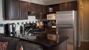 A modern kitchen with dark cabinets, stainless steel appliances, and a central island. - Moguls | Lofted Ski in Ski Out w/ Hot Tub Access (Panorama)