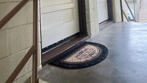 A covered porch with a metal door, a doormat, and a handrail. - Historic Peaceful Apt near VSU & SGMC (Valdosta)