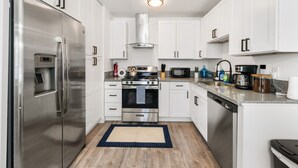 A modern kitchen with white cabinets, stainless steel appliances, and a granite countertop. - 4-Bedroom Cactus-Themed Retreat with Plush Beds (Sacramento)