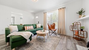 A modern living room with a green sofa, a round coffee table, and a leather chair. - 4-Bedroom Cactus-Themed Retreat with Plush Beds (Sacramento)