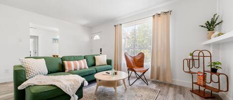 A modern living room with a green sofa, a round coffee table, and a leather chair.