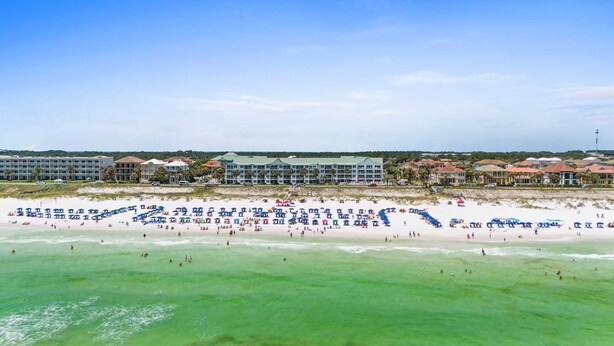 A beachfront hotel with multiple buildings, a sandy beach, and numerous umbrellas. - Maravilla 1201 3/2 pet friendly second floor unit beach service (Miramar Beach)
