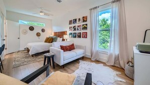 Une chambre moderne avec un lit, un canapé, une petite table et une fenêtre avec des rideaux.