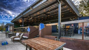 Un espace extérieur aménagé avec des tables et des chaises, une terrasse couverte et un bâtiment portant une enseigne.