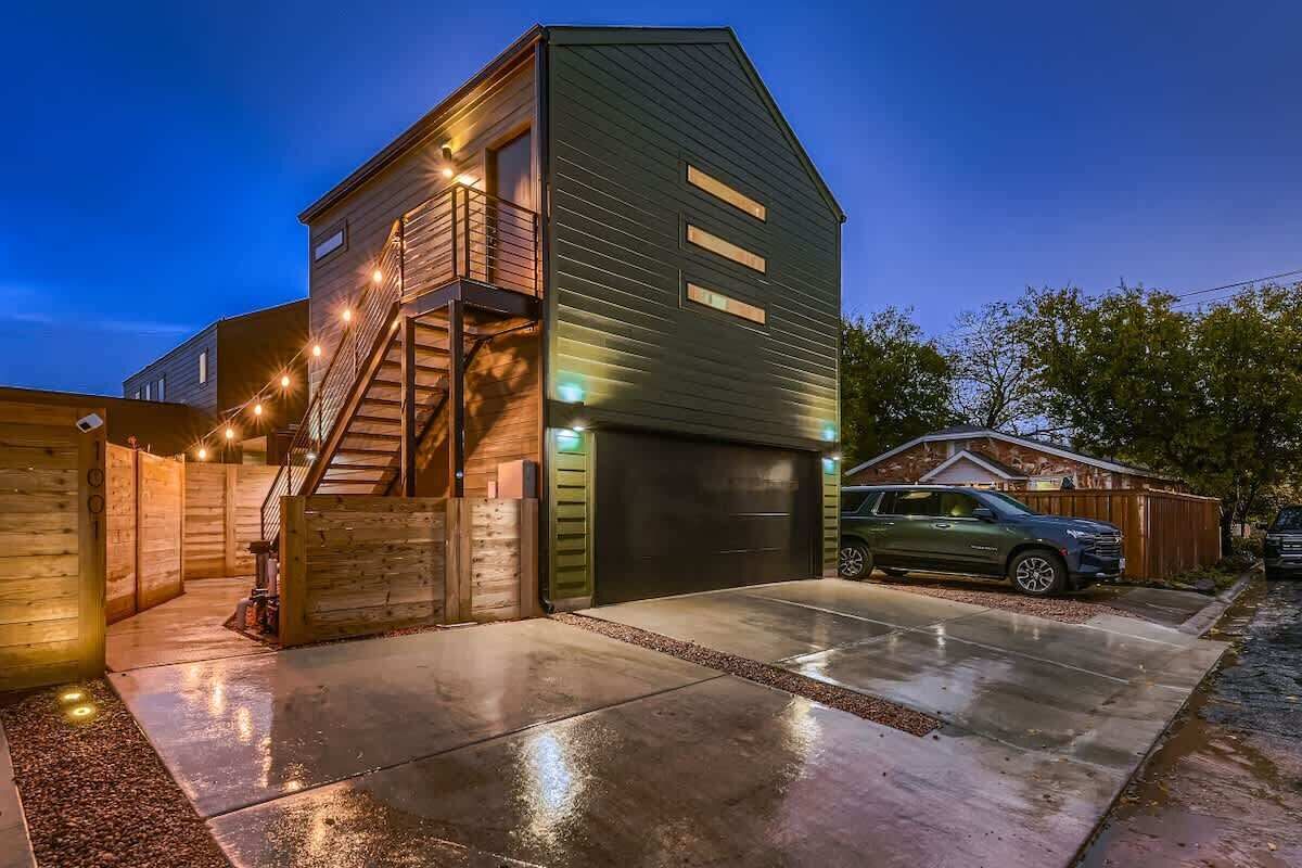 Et moderne hus med to etager, en garage, en trappe og en indkørsel.
