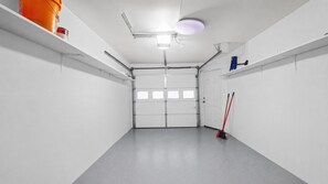 Un garaje limpio y vacío con piso gris, paredes blancas y puerta cerrada.