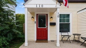 Una casa con puerta roja, número 110, un buzón y una bandera.