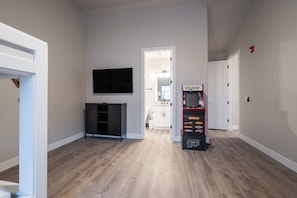 A room with a flat-screen TV mounted on the wall, a black entertainment unit, and a vending machine labeled 'BARBERRY JUPITER'. - Large 5 bedroom with double bunkroom and pool (Hurricane)