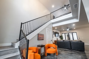 A modern interior with a staircase, a seating area with orange chairs, and a black sofa. - Large 5 bedroom with double bunkroom and pool (Hurricane)