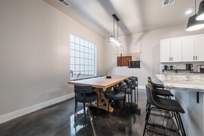 A modern kitchen with a large island, white cabinets, and a large window providing natural light.