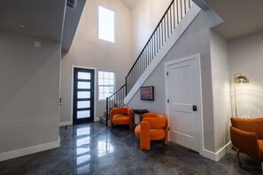 A spacious hallway with a staircase, two orange chairs, and a door with a light fixture. - Large 5 bedroom with double bunkroom and pool (Hurricane)