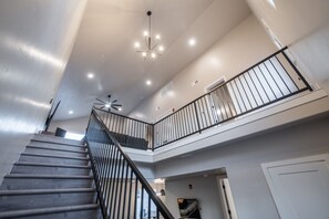 Ein mehrstöckiger Innenraum mit Treppe, Deckenventilator und Geländer.