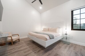 Ein modernes Schlafzimmer mit einem großen Bett, einem Glastisch und einem Sessel.