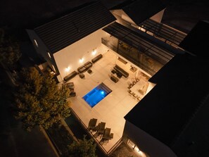 An outdoor swimming pool area with multiple lounge chairs and a hot tub.