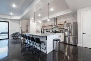 A modern kitchen with a large island, stainless steel appliances, and pendant lighting.