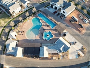 Ett flygbildsfoto av ett bostadsområde med en swimmingpool, en liten fontän och en parkeringsplats.