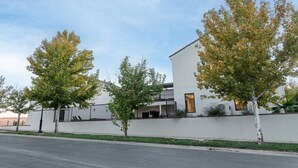 A modern building with a white facade, a balcony, and a tree in front.