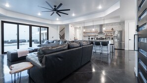 A modern kitchen with a large island, stainless steel appliances, and a bar area.