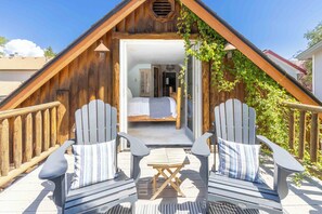 A cozy wooden cabin with a loft bedroom, two Adirondack chairs, and a small table on the deck. - Charming Ketchum Cottage with Gourmet Kitchen (Ketchum)