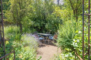A garden with a table and chairs, surrounded by dense foliage and a metal fence. - Charming Ketchum Cottage with Gourmet Kitchen (Ketchum)