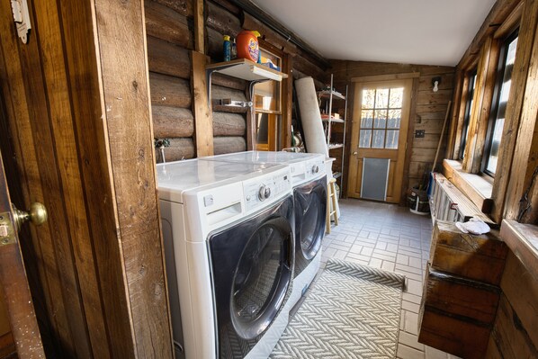 A laundry room with a washing machine and dryer, wooden walls, and a window. - Charming Ketchum Cottage with Gourmet Kitchen (Ketchum)